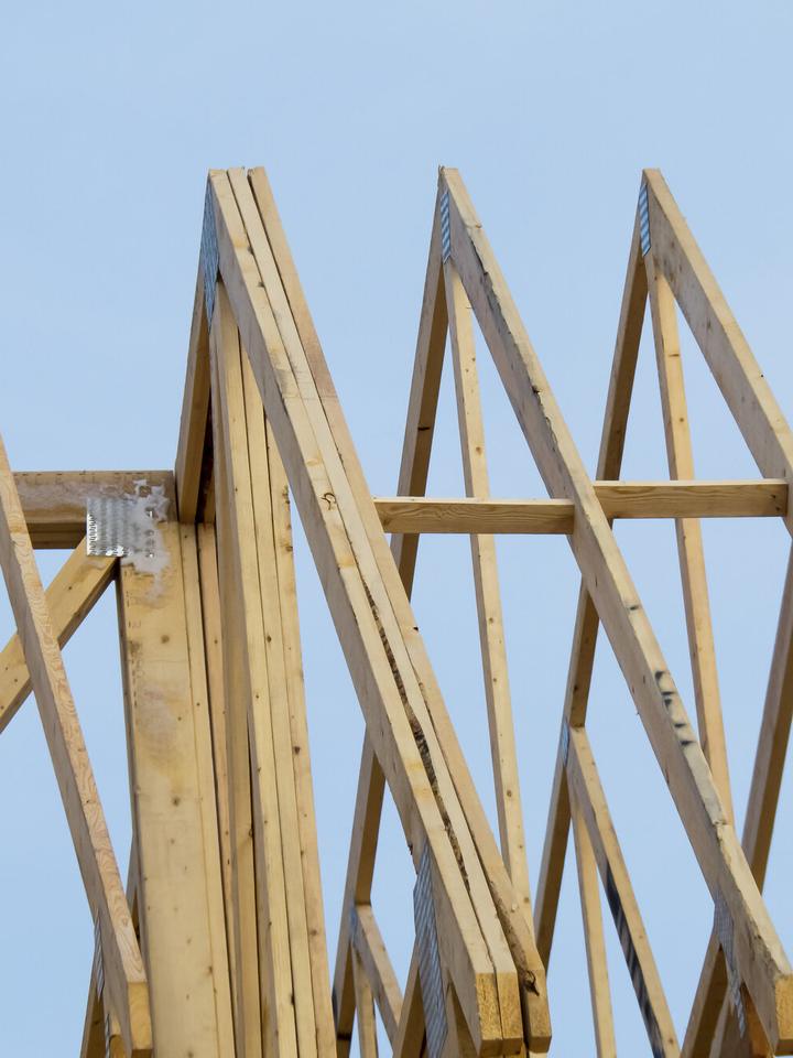 Dachbinder aus Holz mit Nagelplatten an den Knoten vor hellem Himmel